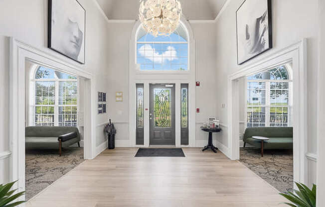A hallway with a chandelier, two sofas, and pictures on the wall.