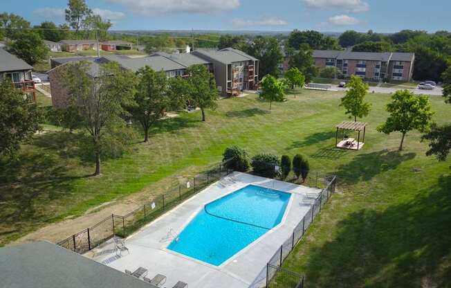 A swimming pool surrounded by a fence and trees in a residential area.