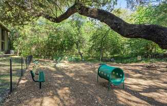 A playground with a green slide and a green bench.
