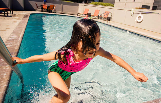 a little girl jumping into a swimming pool