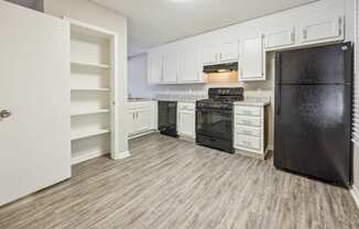 an empty kitchen with white cabinets and black appliances