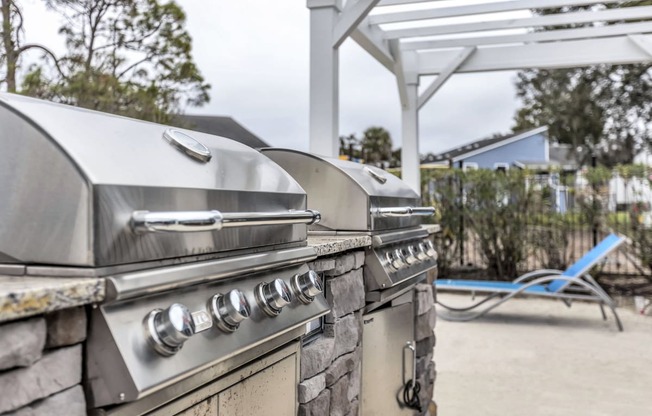 two gas bbq grills in a backyard with a picnic table