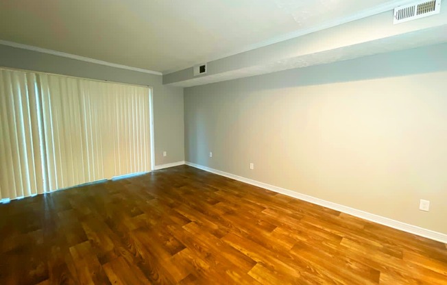 a bedroom with hardwood floors and a large window