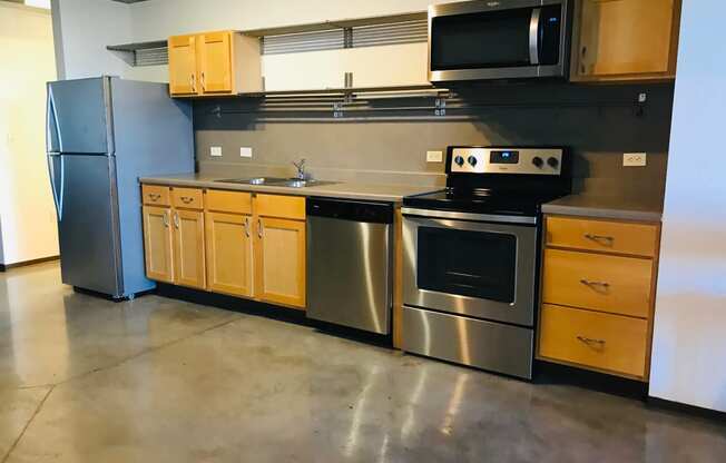 an empty kitchen with stainless steel appliances and wooden cabinets