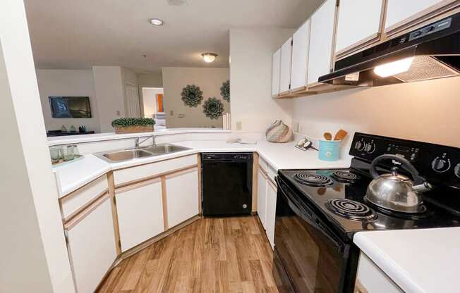 The Crest at Berkeley Lake model apartment kitchen with wood cabinets and black appliances located in Duluth, GA 30096