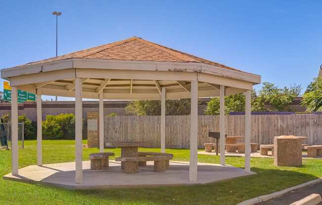 A pavilion with a red roof and a wooden bench in front of it.