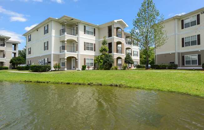 A large apartment complex with a pond in front.