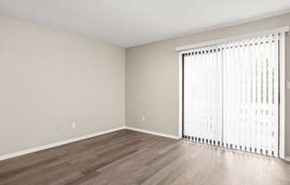 an empty living room with a large window and wood flooring