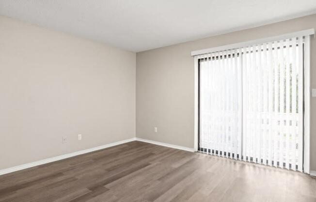 an empty living room with a large window and wood flooring