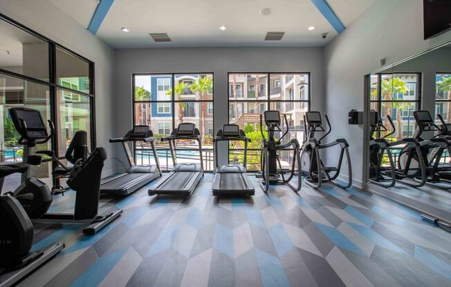 a gym with cardio equipment and windows in a building