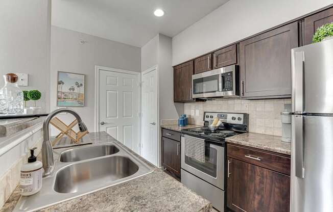 A kitchen with a stainless steel refrigerator, oven, and sink.