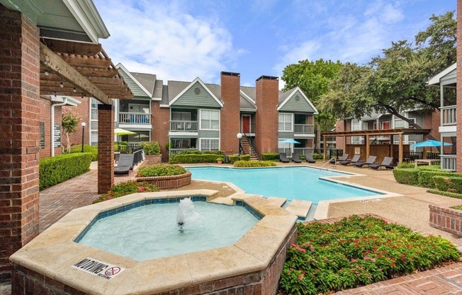 a swimming pool with a fountain in front of an apartment building