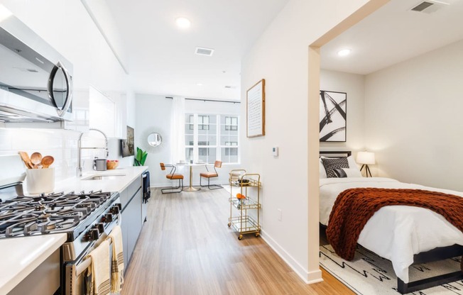 a bedroom with a bed and a kitchen with a stove at One Ten Apartments, Jersey City , New Jersey