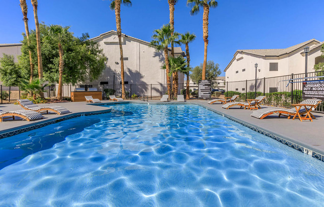 A swimming pool surrounded by palm trees and lounge chairs.