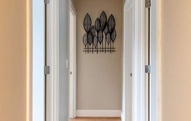 A hallway with a white door and a wall hanging.