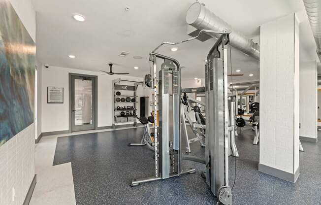 A gym with a variety of equipment including a treadmill, a weight machine and a rowing machine.