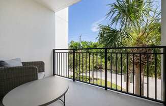 a balcony with a table and chairs and a palm tree