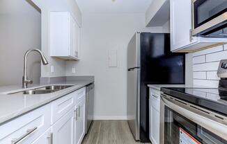 a kitchen with white cabinets and black appliances