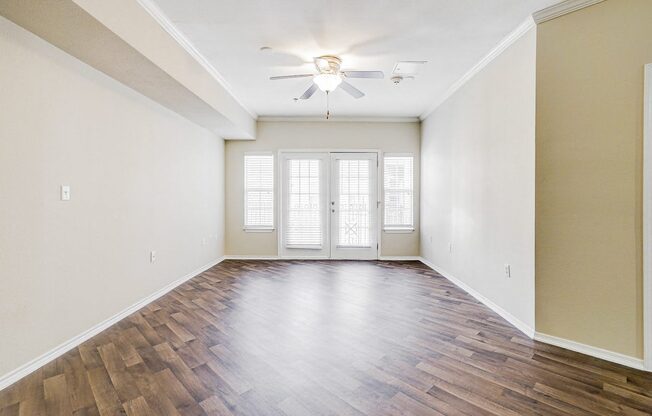 an empty living room with wood flooring and a ceiling fan