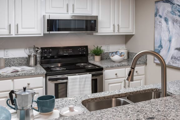 stainless steel appliances, white cabinetry, granite countertops, and modern fixtures in kitchen at Preserve at Cedar River Apartments, Jacksonville