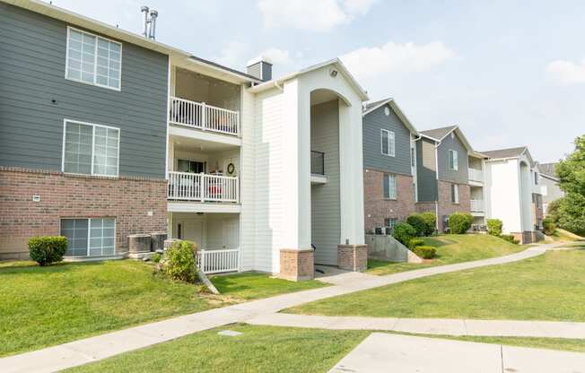 the outlook of two story apartment buildings with sidewalks and grass