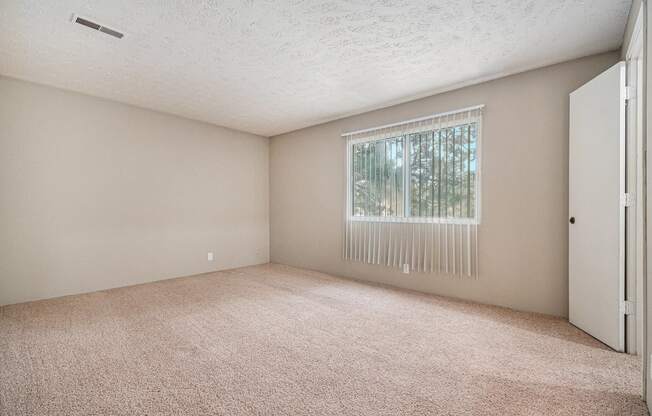 Omaha, NE Evergreen Terrace Apartments. A bedroom with a large window and beige carpet