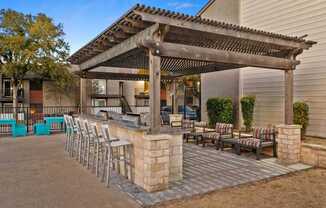 A patio with a pergola and chairs is set up outside a house.