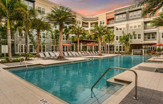 A swimming pool surrounded by palm trees and lounge chairs.
