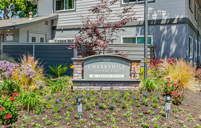 Cherry Hill Apartments is a housing complex with a well-maintained garden in front.