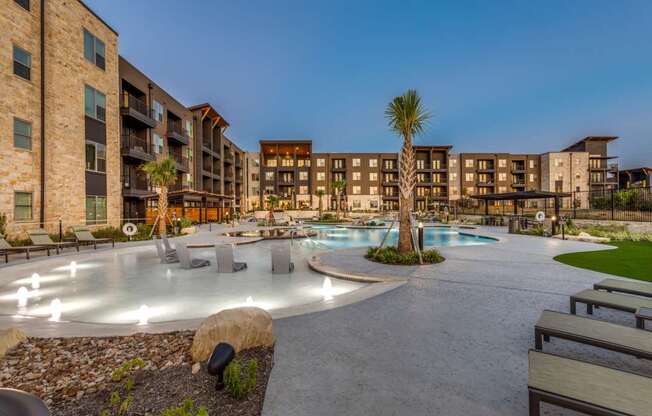 A pool area with a palm tree in the middle of a courtyard surrounded by buildings.