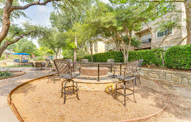 A backyard with a fire pit and chairs.