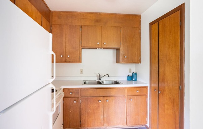 a small kitchen with wooden cabinets and a white refrigerator. Fargo, ND Luxford Apartments