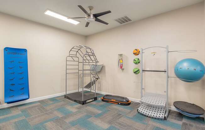 a workout room with a yoga ball and a ceiling fan