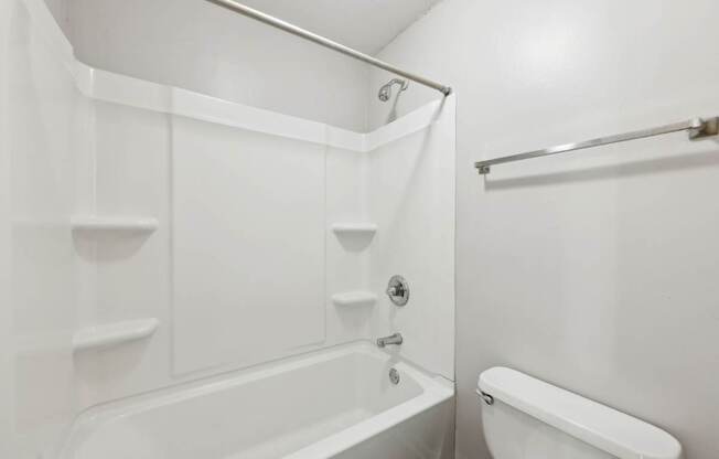 A white bathroom with a tub and toilet at Gwinnett Square Apartments in Duluth, GA