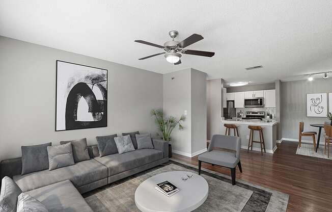 Model Living Room with Wood-Style Flooring and View of Kitchen/Dining Area at Fountains Lee Vista Apartments in Orlando, FL.