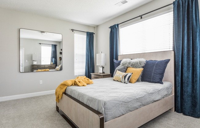 Bright and spacious apartment bedroom with carpeting and multiple large windows