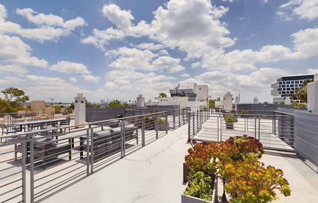 A rooftop patio with tables and chairs overlooking a city skyline.