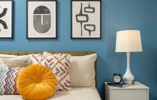 a bedroom with a blue wall and three pieces of art above the bed