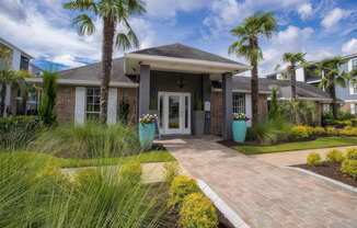 a home with a walkway and palm trees in front of it