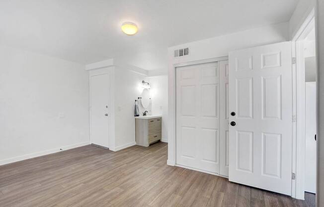 A room with white doors and a cabinet with a lamp on it.