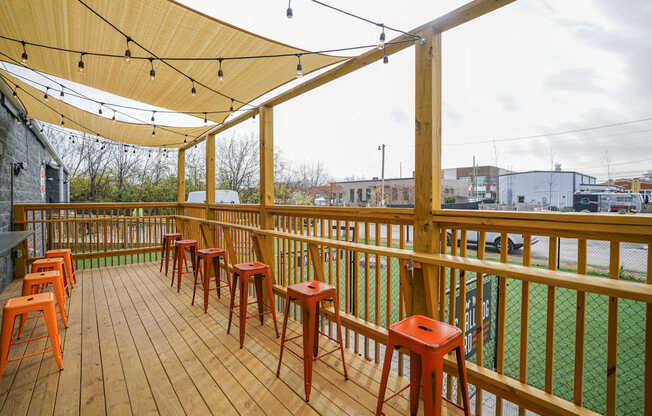 A wooden deck with orange stools and a yellow canopy.