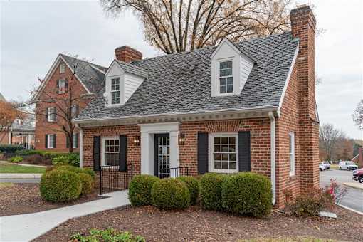 A small brick house with a black door and a white window.