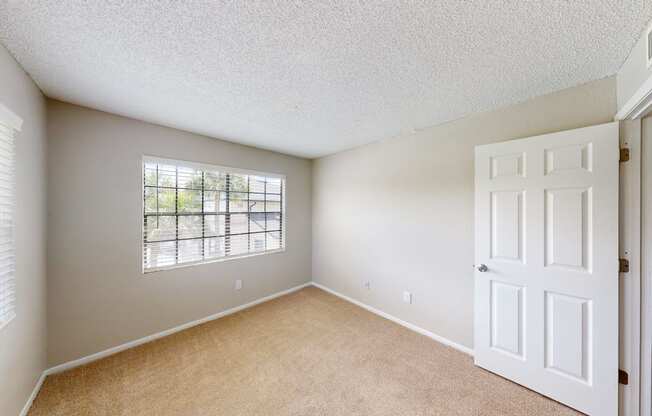 a bedroom with a large window and a white door