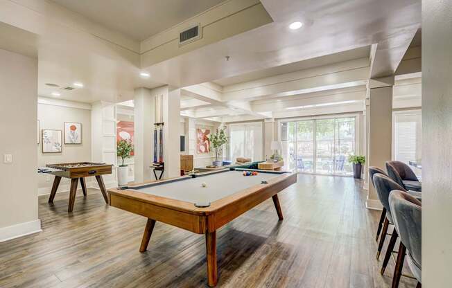 A pool table is in the middle of a room with a lot of windows.