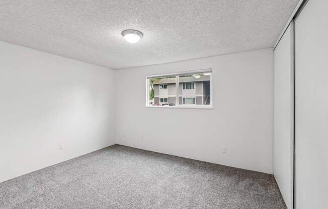 A room with a window and carpeted floor.