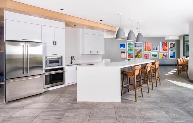 Club kitchen with island seating, stainless steel appliances, and vibrant local artwork.
