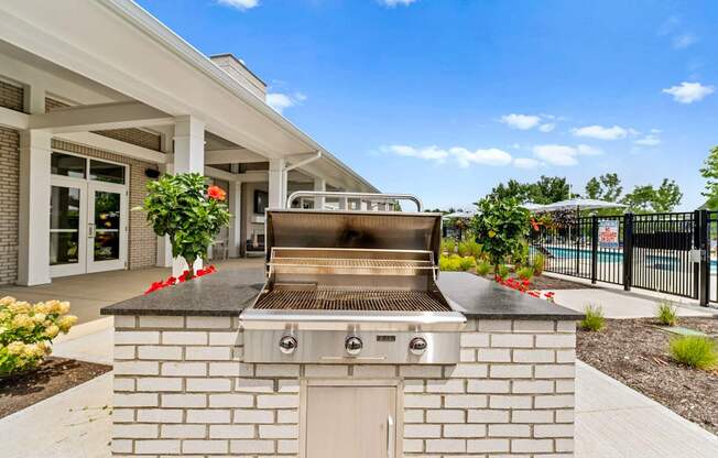 A modern outdoor kitchen with a built-in grill and a white brick exterior.