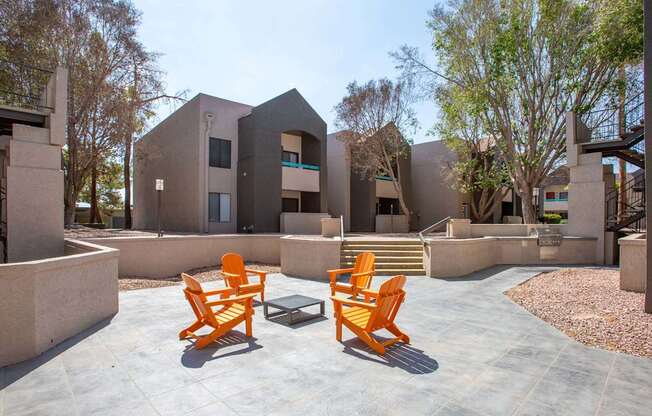 Two orange chairs are placed on a patio in front of a building.