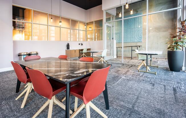a conference room with a glass table and red chairs