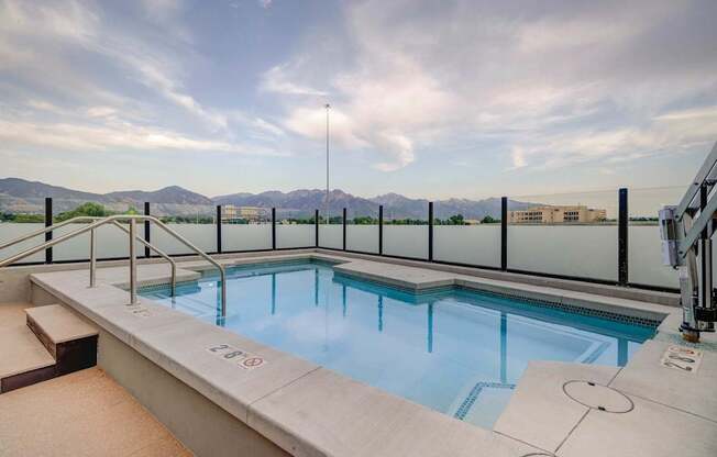 A small indoor pool with a glass railing and a mountain view.